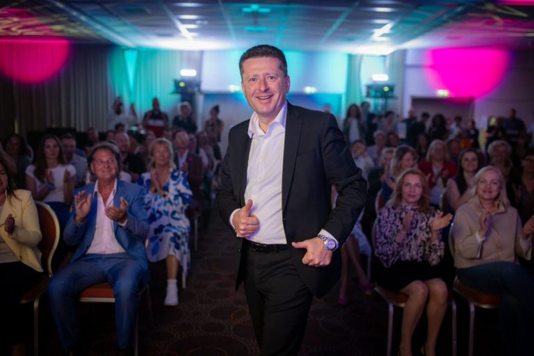 Sascha Höthke steht lächelnd vor einem begeisterten und applaudierenden Publikum.